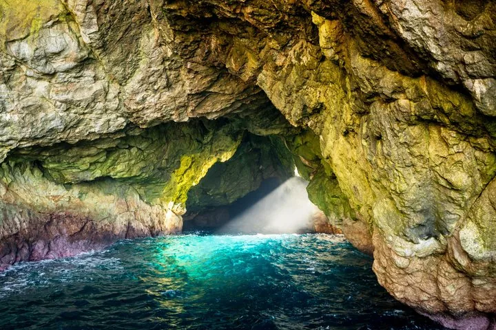 Sonnenlicht fällt durch eine Öffnung in eine dunkle, felsige Meereshöhle