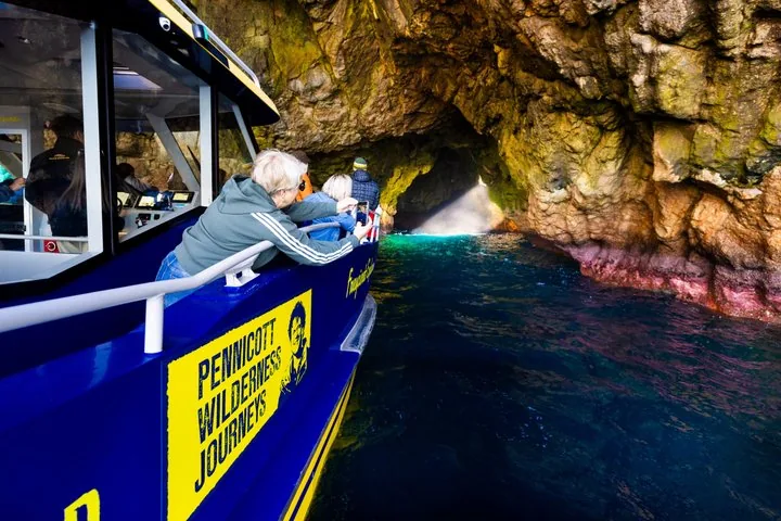 Passagiere auf einem Ausflugsboot, die in einer großen Meereshöhle Fotos machen